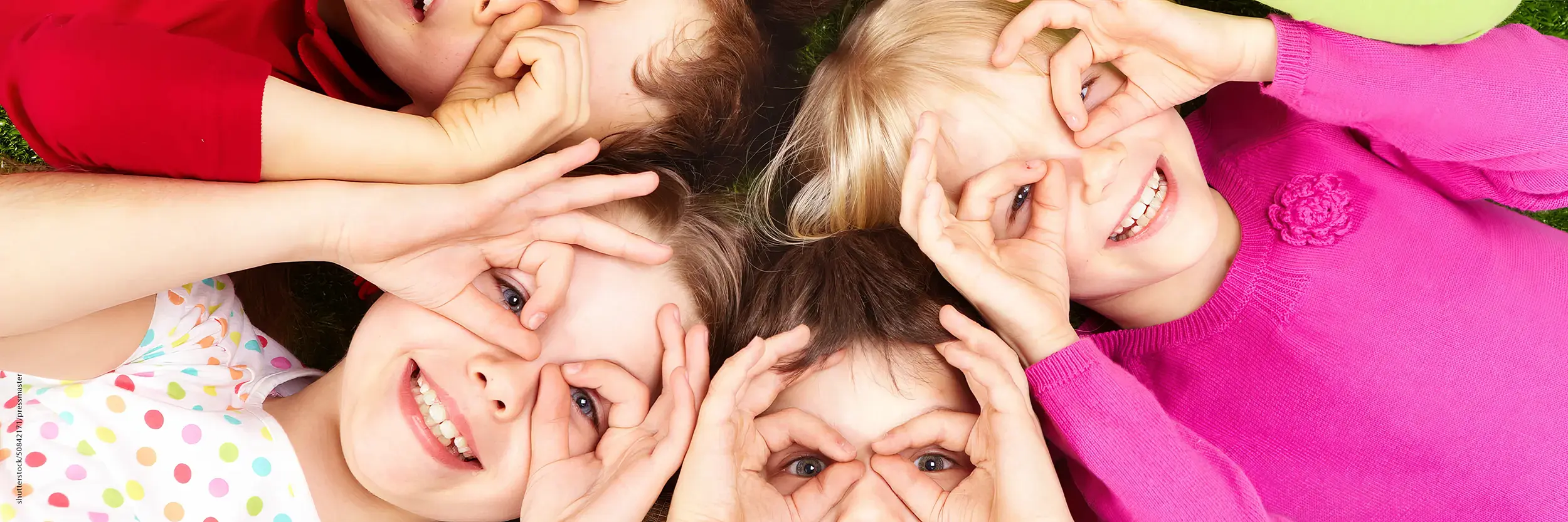 Kinder liegen am Boden und schauen durch die Finger